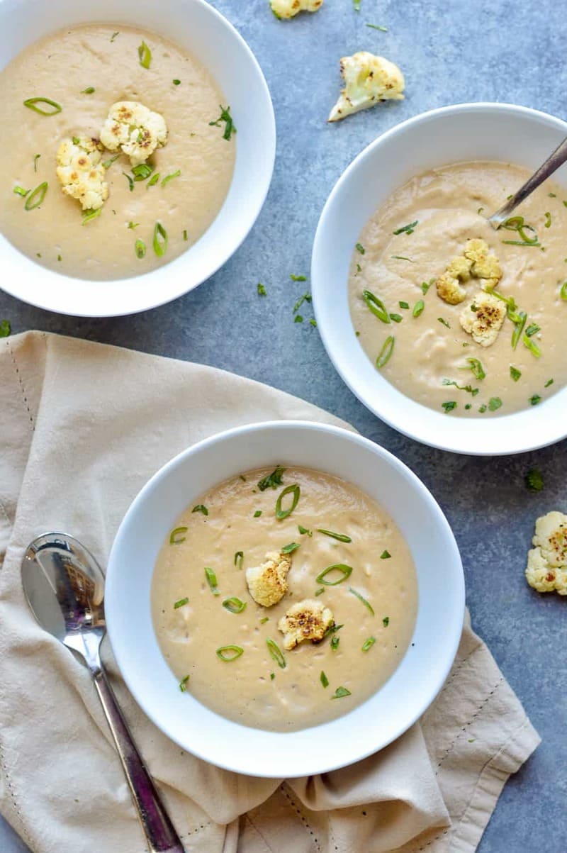 Cauliflower- and potatosoup with springonion in white bowls.