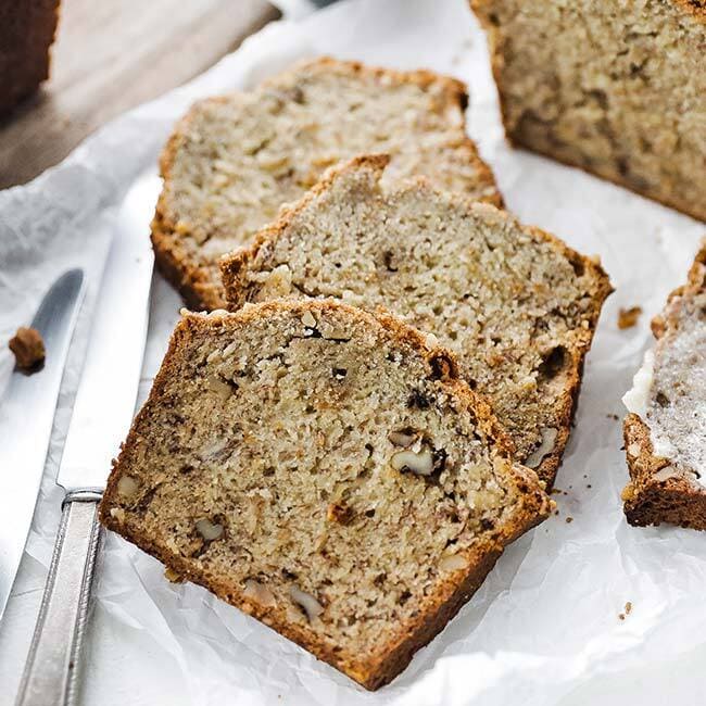 Bananabread with walnuts on a white paper with a knife.