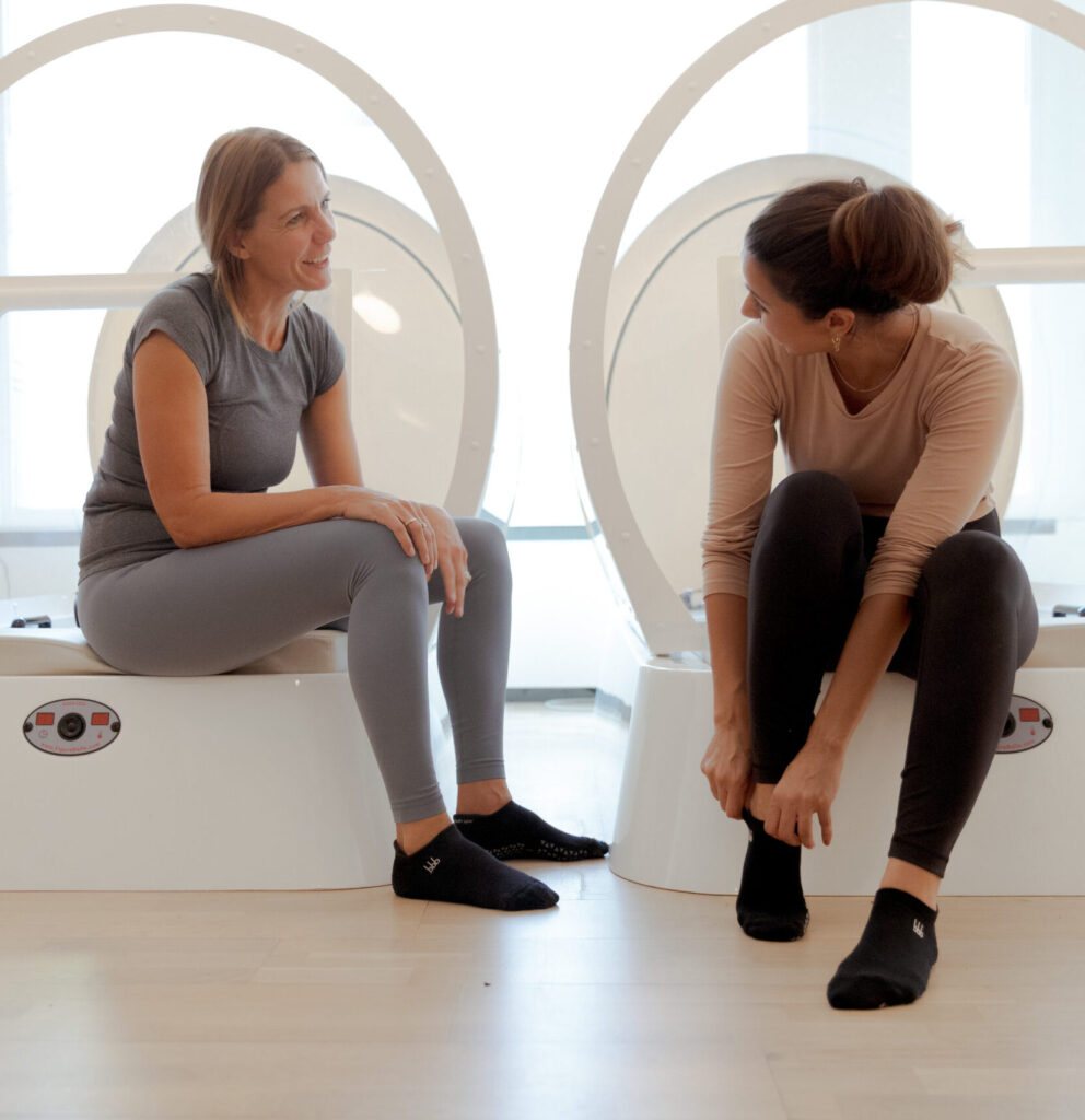 Twee vrouwen sporten samen in een holistische sportschool bij bbb health boutique amsterdam. Ze hebben gripsokken aan.