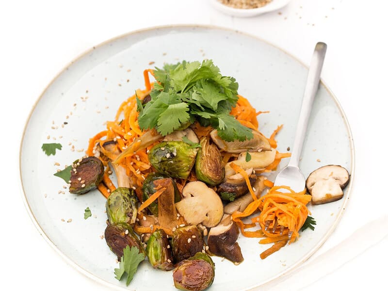 Noodles van zoete aardappel met spruitjes, champignons en koriander.