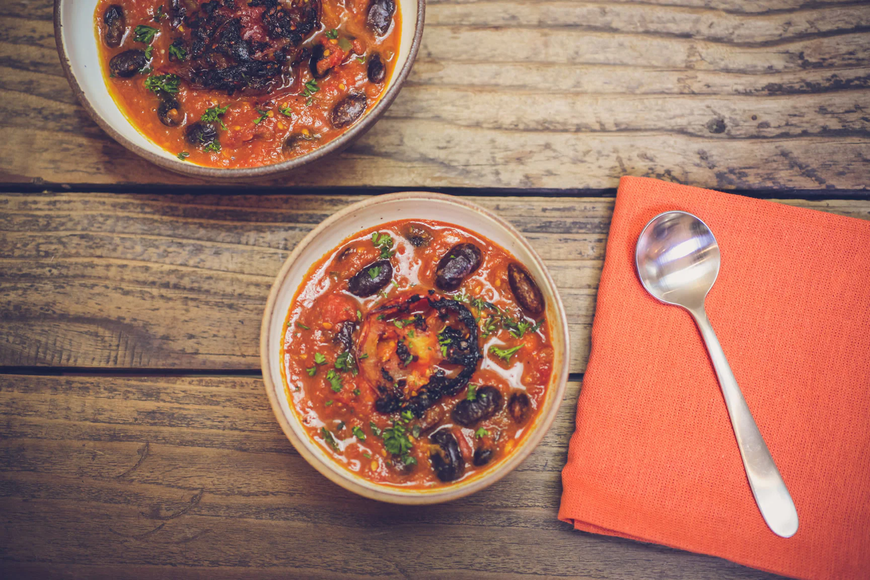 A bowl of runner beans with bell pepper and tomato and a spoon.