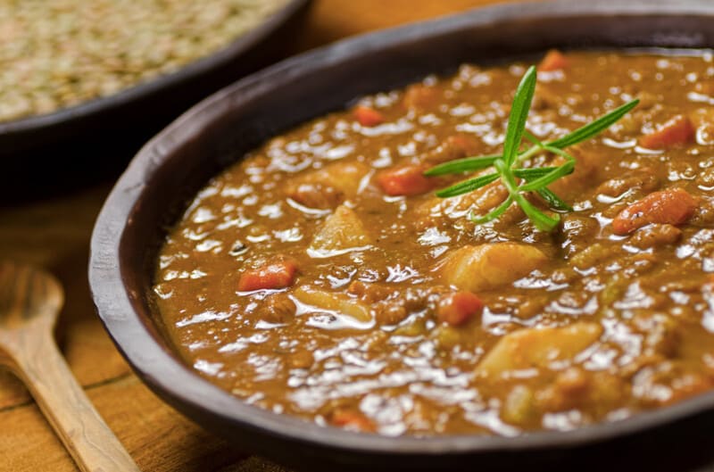 Vegan stoofpot met linzen geserveerd in een kom, gegarneerd met rozemarijn.