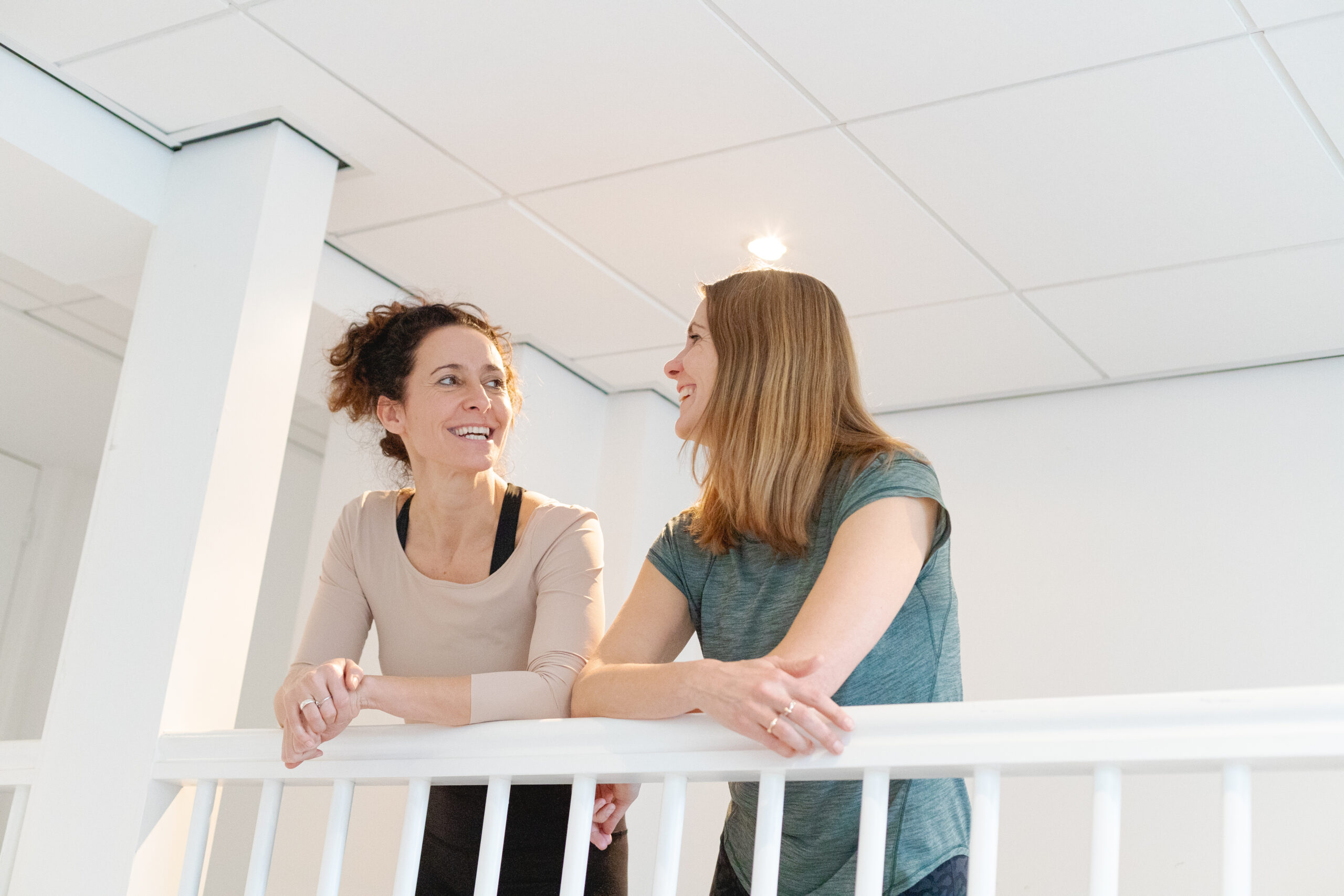 Oprichters Esther en Inge staan samen te praten in de groepsleszaal bij bbb health boutique, een holistische sportschool voor vrouwen in Amsterdam en Utrecht.