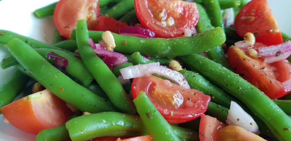 Salade met haricot verts, tomaten, ui en pijnboompitten.