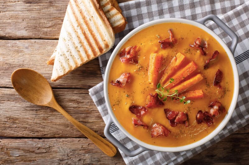 Curry carrot- and potato meal soup in a bowl with toast.