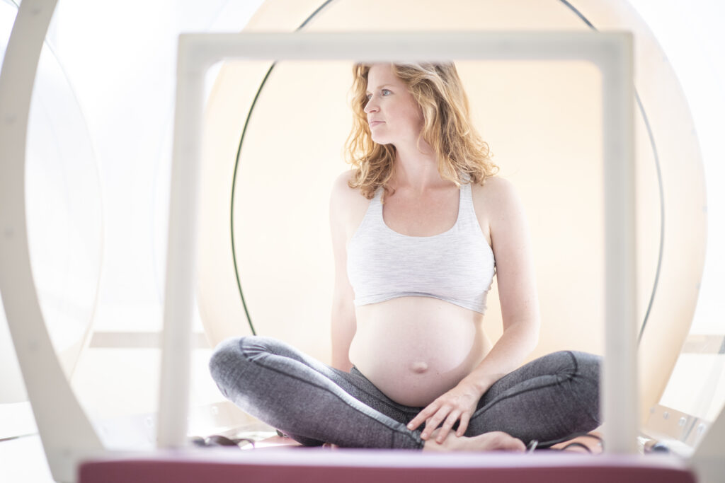 Een zwangere vrouw is aan het sporten bij bbb health boutique Amsterdam in een warmtecabine.