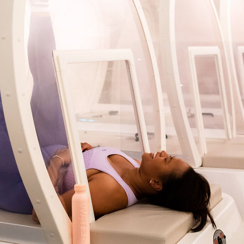 Woman laughs during a workout in the hot cabin of bbb health boutique.