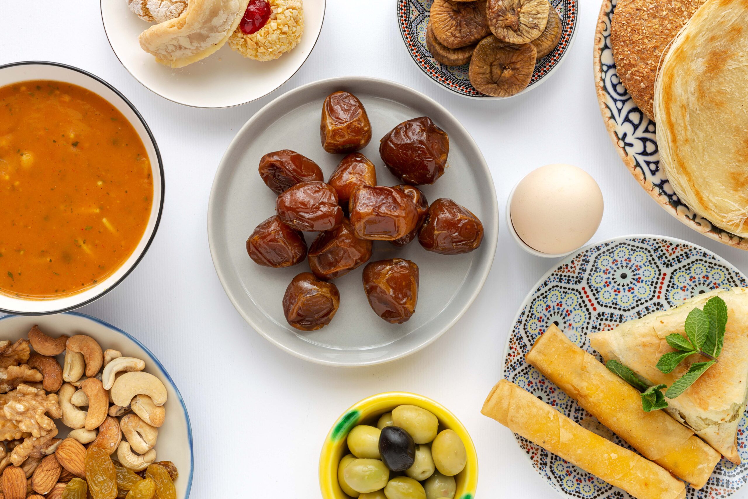 Table filled with various small ramadan dishes such as dates, harira, olives, and nuts.