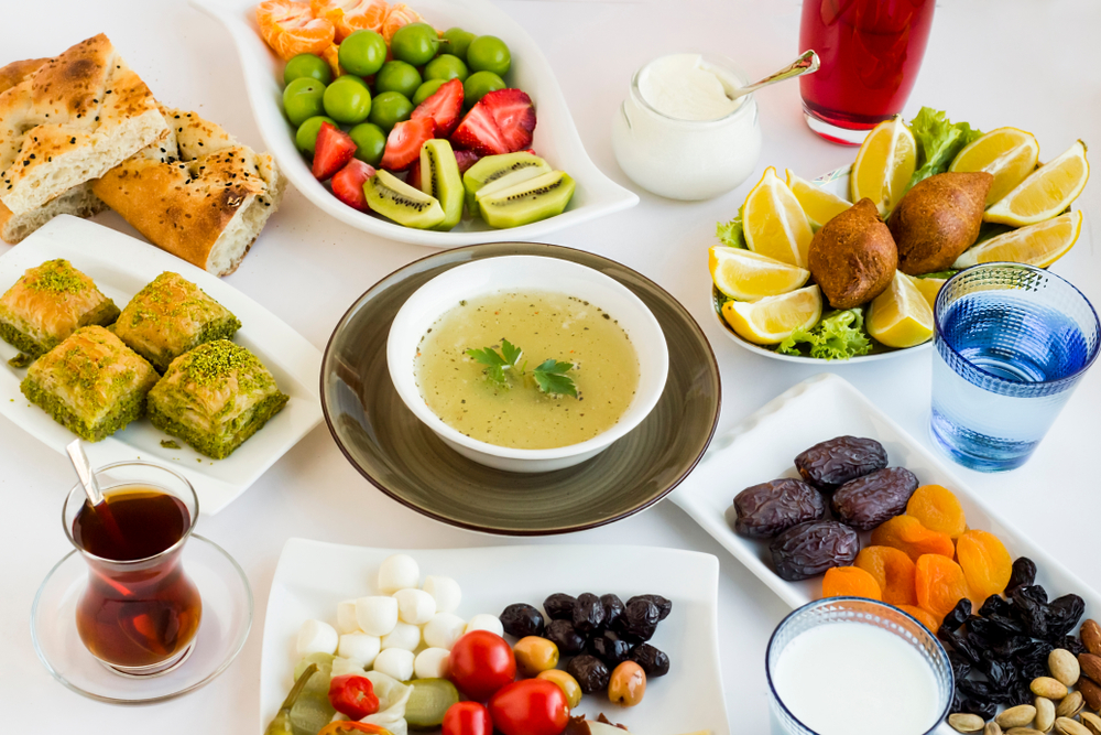 Table with Ramadan dishes such as fresh and dried fruits, vegetables, and soup.